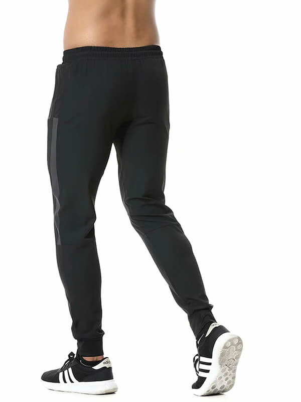 Men's athletic soccer running trousers with zip pockets, black, shown from the back with elastic waistband for sports activities.