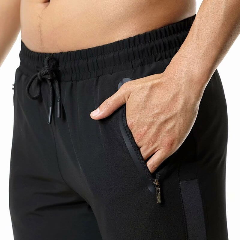 Close-up of men's athletic soccer running trousers with zip pockets and elastic waistband, highlighting flexibility and comfort.