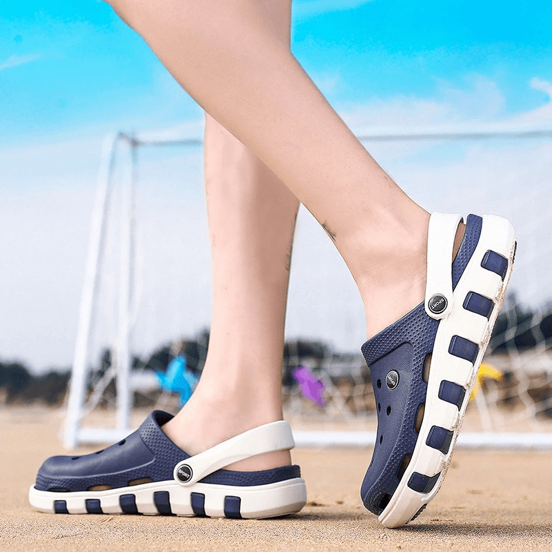 Person wearing navy quick-drying sandals with anti-slip soles on a sandy beach.