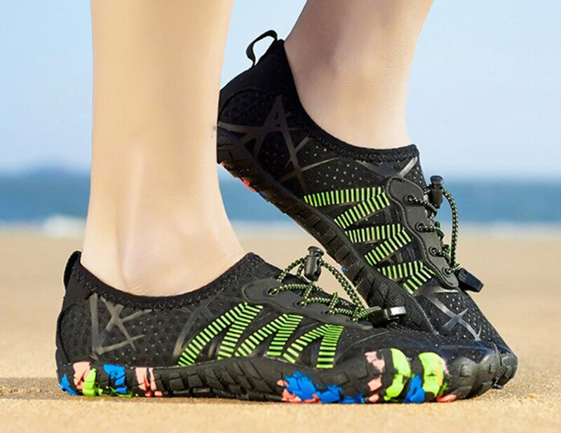 Unisex beach quick-dry lace-up shoes, black with green accents, showcased on sandy shore, perfect for water activities. Model: SF0472.