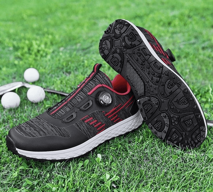 Black and red lace-up breathable sneakers on grass, showcasing durable rubber sole and air mesh upper for comfort and flexibility.