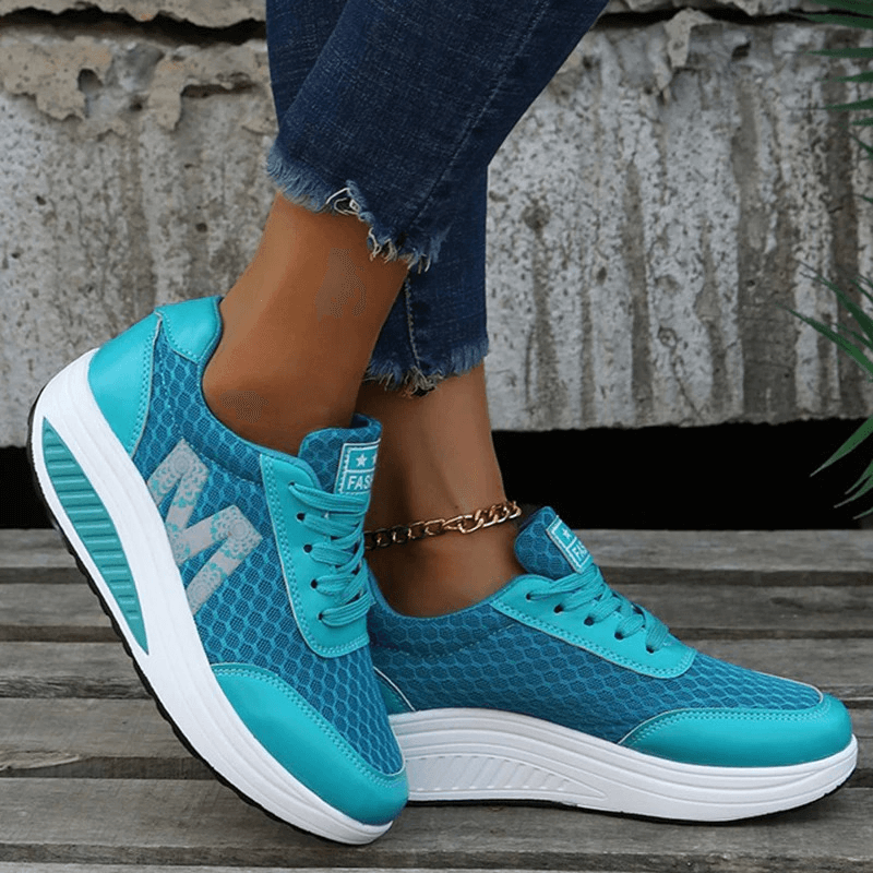 Blue breathable mesh sneakers with thick white sole, lace-up design, round toe, and stylish detailing, worn casually on a stone background.