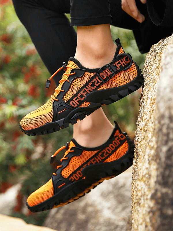 Vibrant orange breathable mesh trekking shoes with rubber outsole, perfect for outdoor adventures and stylish, unisex sports sneakers.