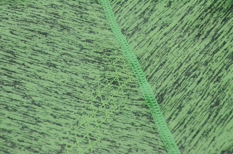 Close-up of green breathable t-shirt fabric showing detailed stitching, perfect for active wear and quick-drying performance.