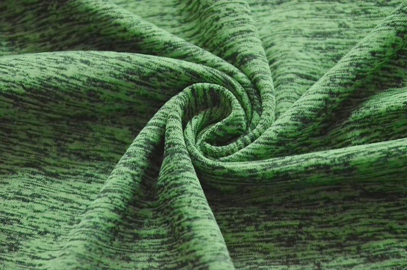 Close-up of green breathable fabric texture for women's quick-dry t-shirt, showcasing water-resistant and durable material swirl design.