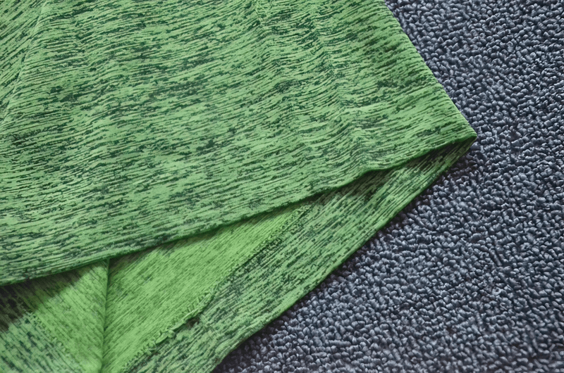 Close-up of a green breathable women's short sleeve t-shirt fabric, highlighting texture and water-resistant material, ideal for sports activities.
