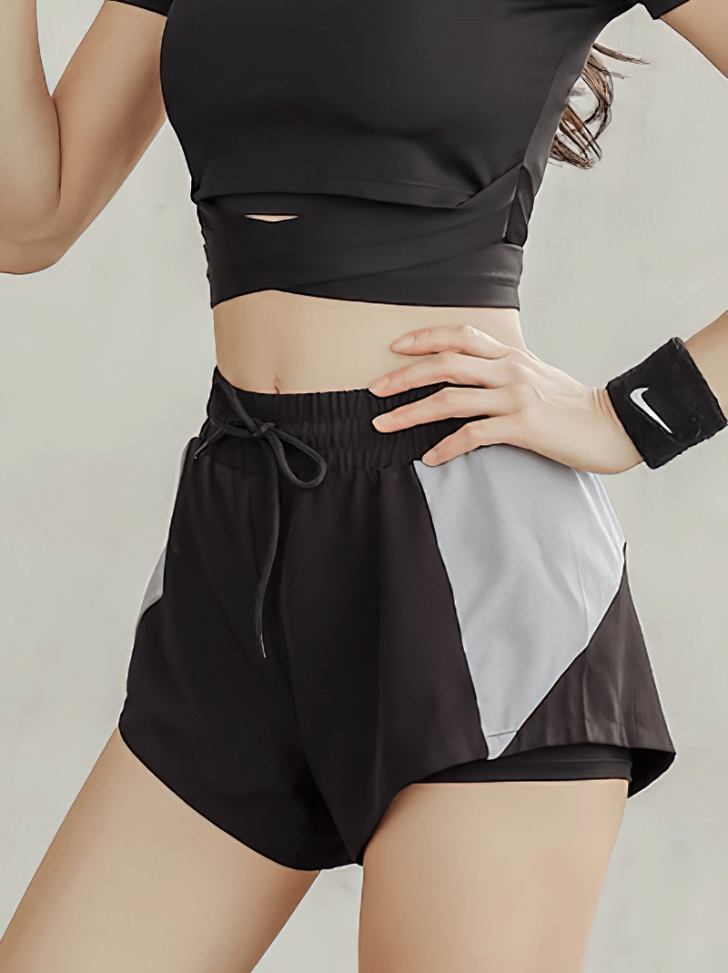 Woman wearing black casual breathable elastic waist sports shorts with patchwork design