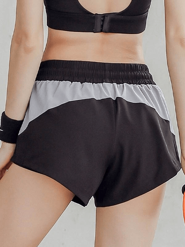 Back view of black casual breathable elastic waist sports shorts with patchwork design, perfect for female athletes.