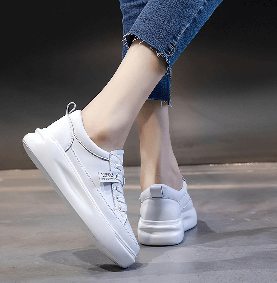White leather platform sneakers with lace-up design, worn with cropped jeans, featuring breathable and casual sporty style.