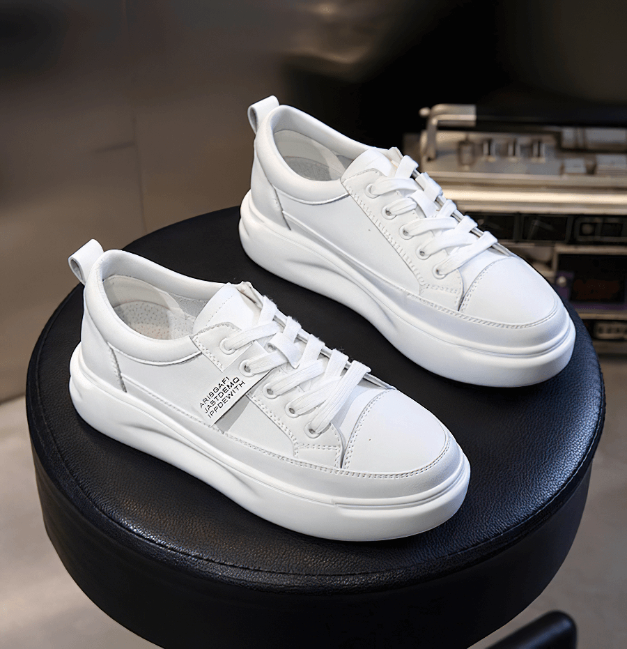 White casual breathable lace-up sports leather platform sneakers on a black stool.