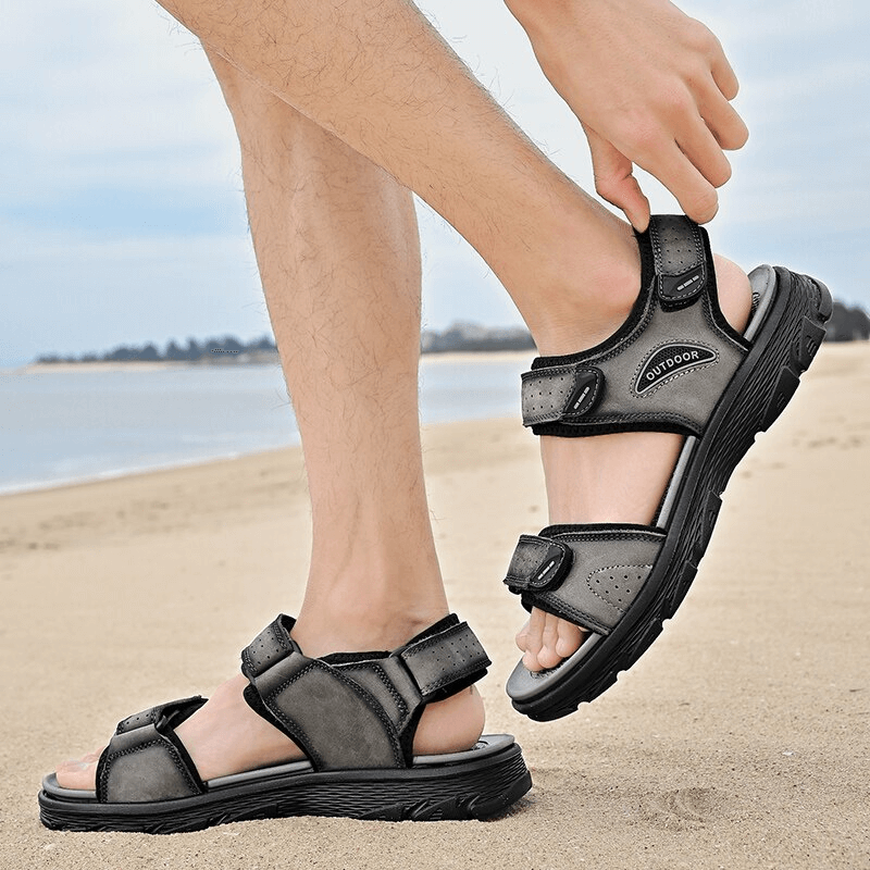 Men's genuine leather hiking sandals with soft soles in black, ideal for casual wear and trekking, shown on a sandy beach.