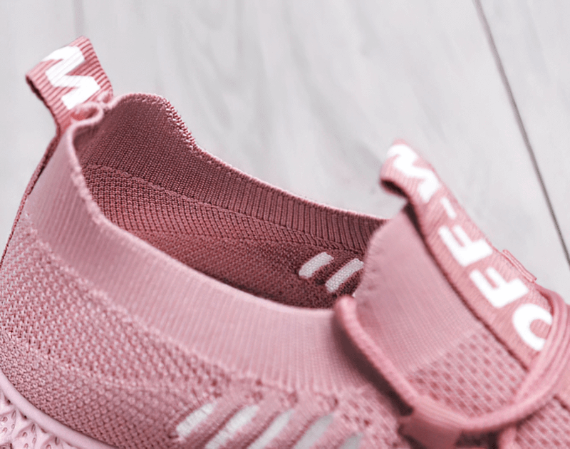 Close-up of pink mesh breathable sneaker with lace-up design and flat bottom, featuring fabric lining for comfort.