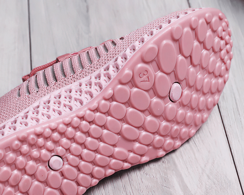Close-up of pink flat bottom sole of mesh breathable sneaker, showcasing unique tread pattern for women’s casual lace-up shoes.