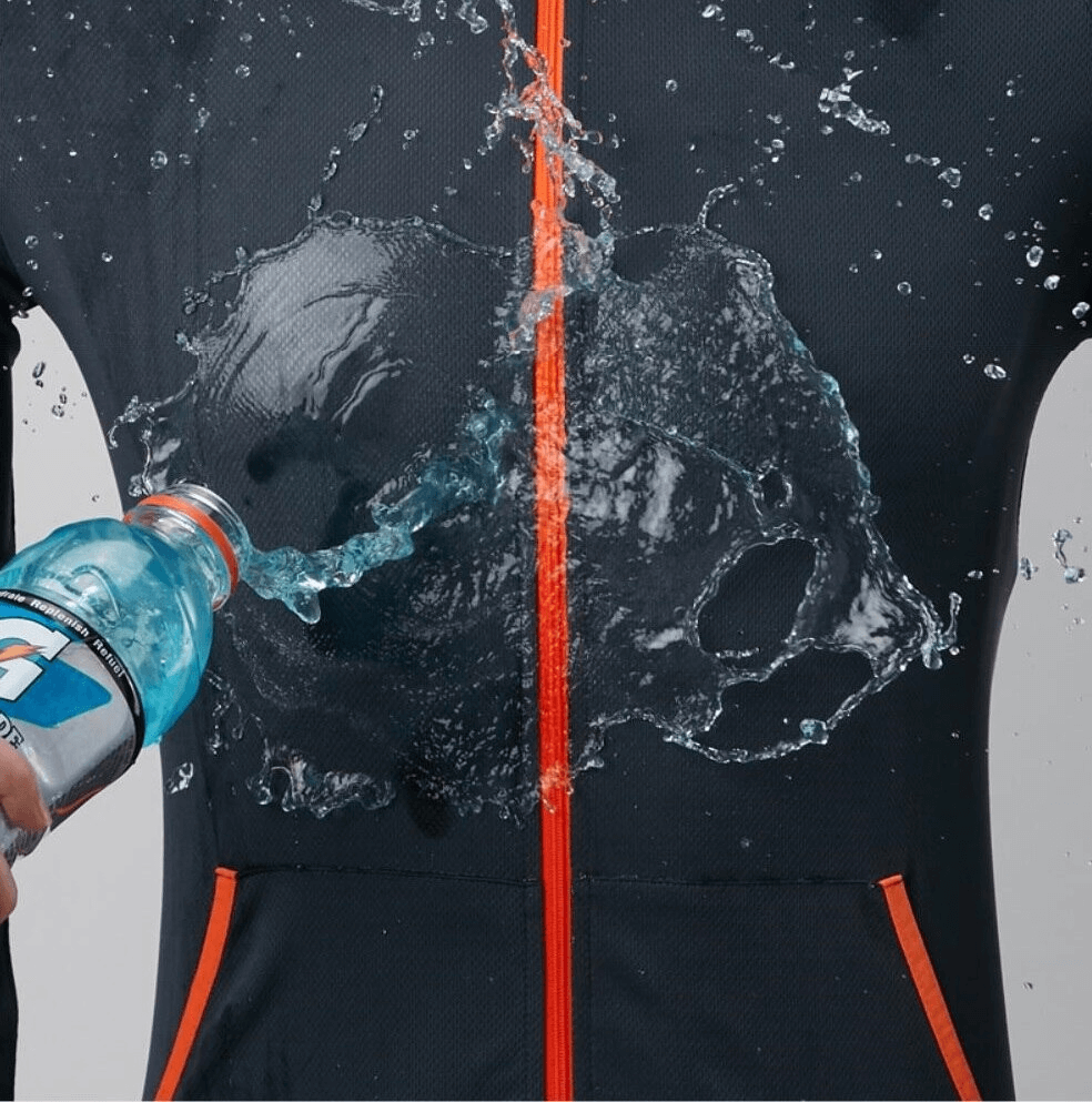 Waterproof men's sunscreen jacket being splashed with water, showcasing its water-resistant properties and stylish design with orange accents.