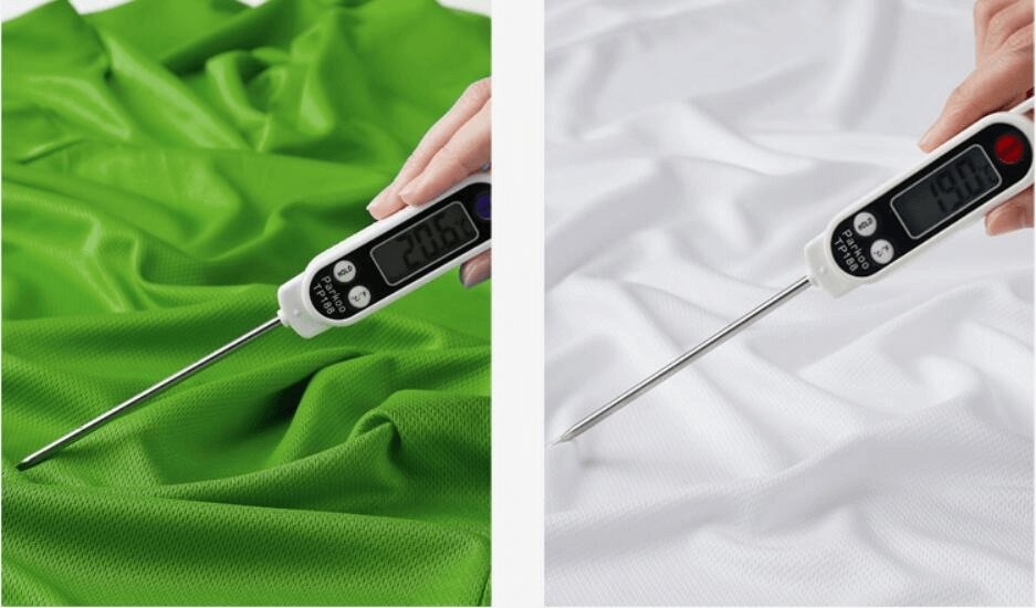 Digital thermometer displaying temperatures on green and white fabrics, demonstrating temperature difference and fabric cooling effectiveness.