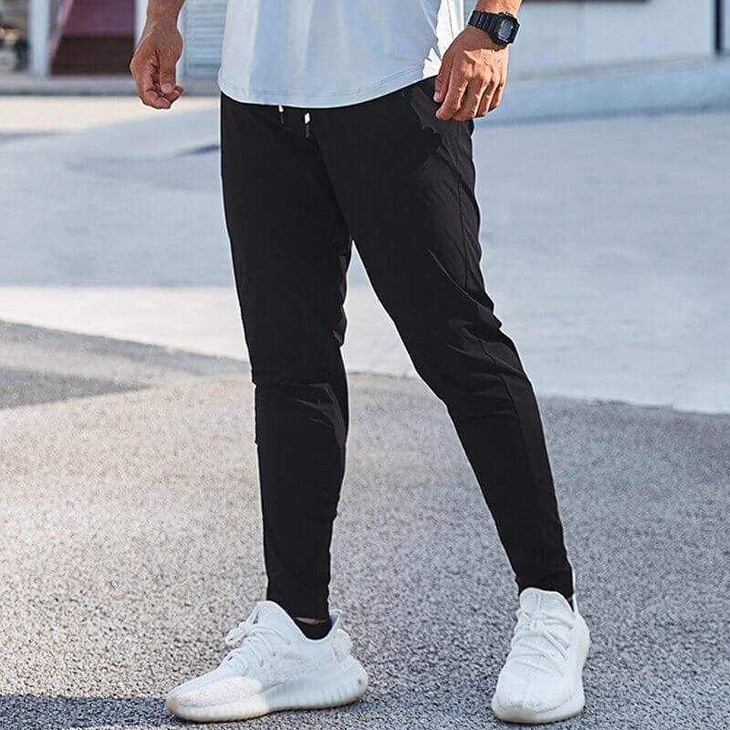 Man wearing casual male long sweatpants for running, featuring an elastic waist, made from polyester and spandex blend.