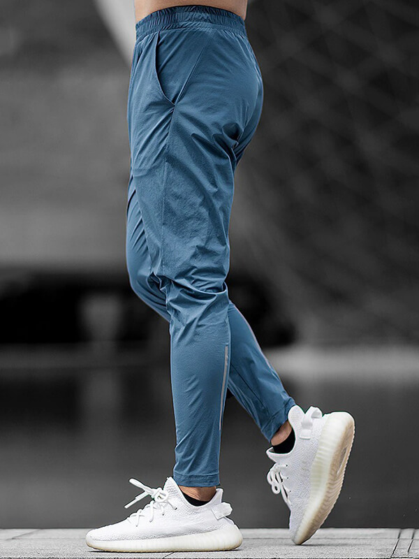 Man wearing blue casual long sweatpants with elastic waist for running, paired with white sneakers.