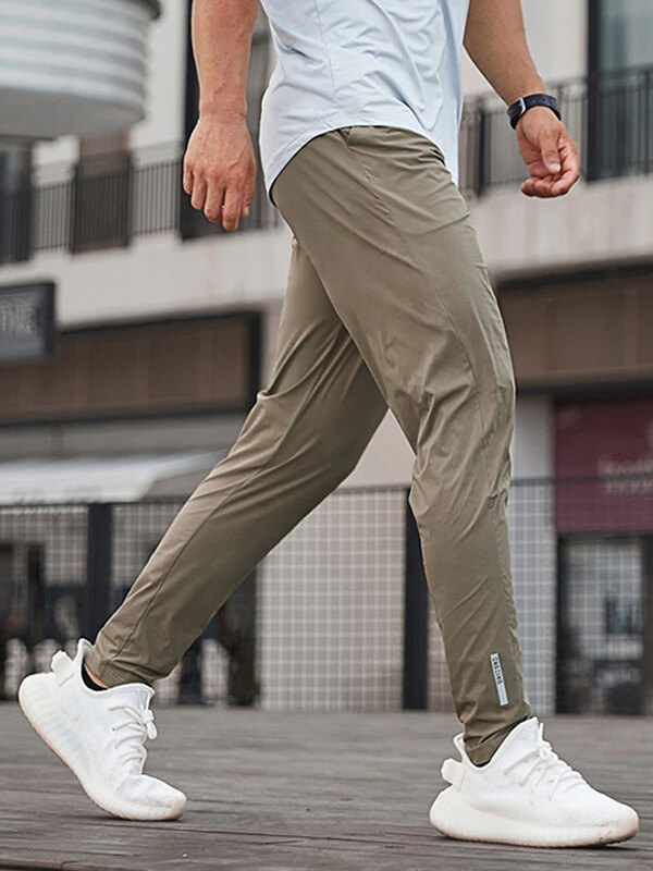 Male wearing casual long sweatpants for running, in a full-length design with elastic waist, made of polyester and spandex blend.