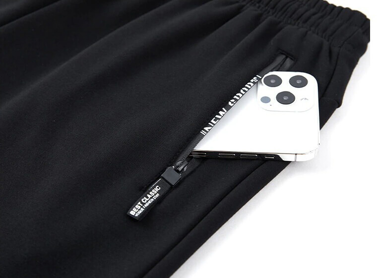 Black men's windproof pants with zippered pocket holding a smartphone.
