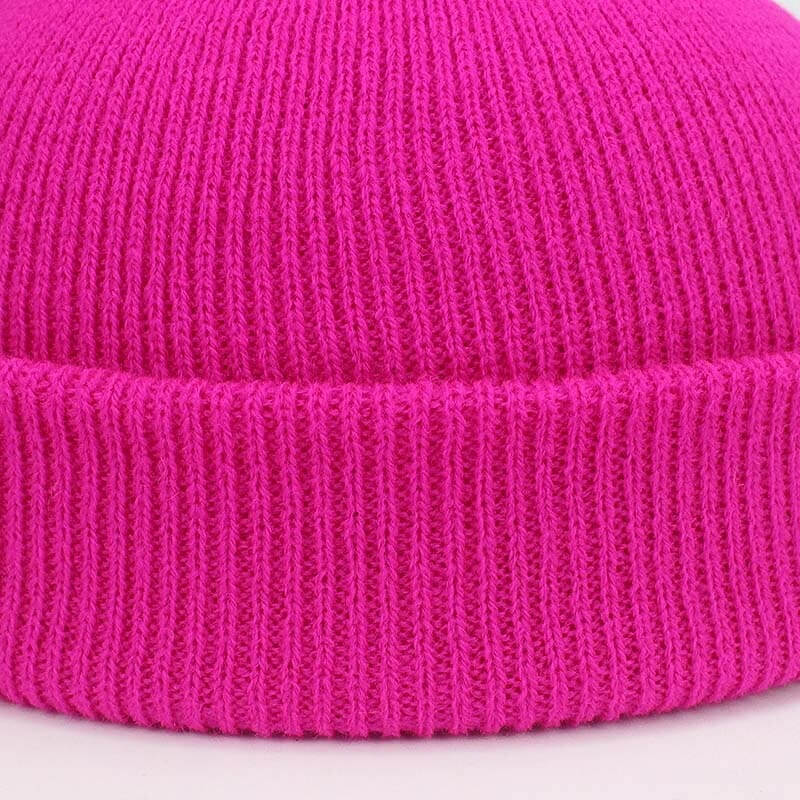 Bright pink knitted beanie displaying close-up of fabric texture, ideal for winter warmth. Casual unisex style, soft and thick material.