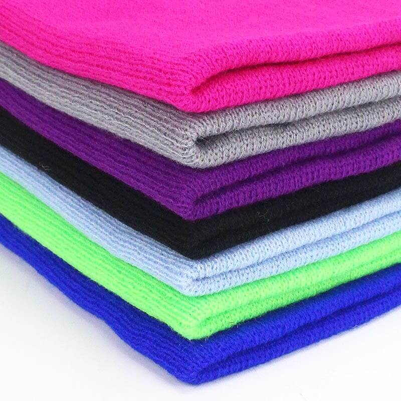 Stack of colorful knitted beanies in pink, grey, purple, black, light blue, green, and bright blue, perfect for keeping warm in style.
