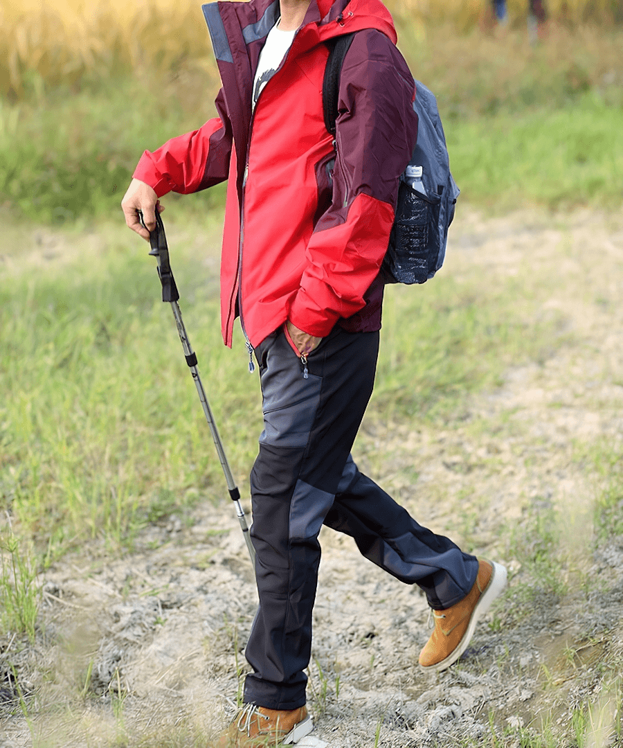 Person hiking outdoors in cold resistance waterproof fleece pants and red jacket, showcasing durability and warmth.