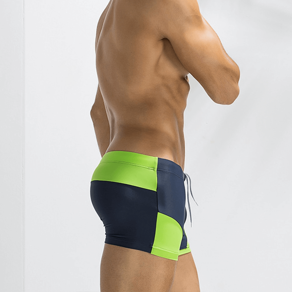 Side view of a man wearing color block swimming boxer shorts in navy and neon green.
