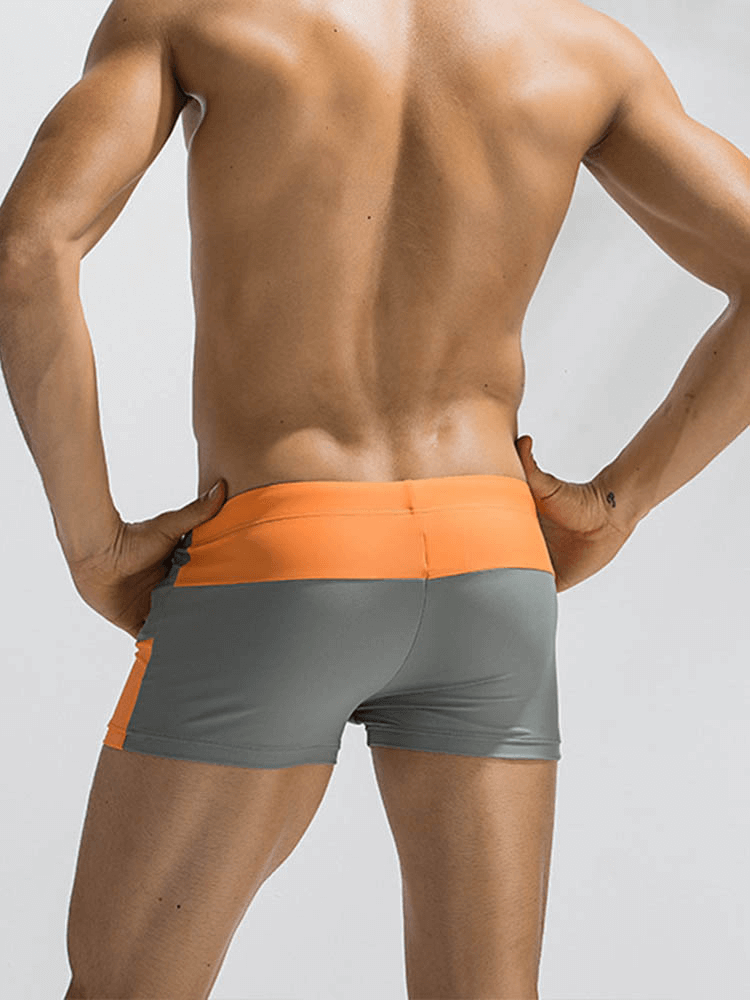 Back view of color block swimming boxer shorts for men in orange and gray, highlighting minimalist design and elastic fit for sports.
