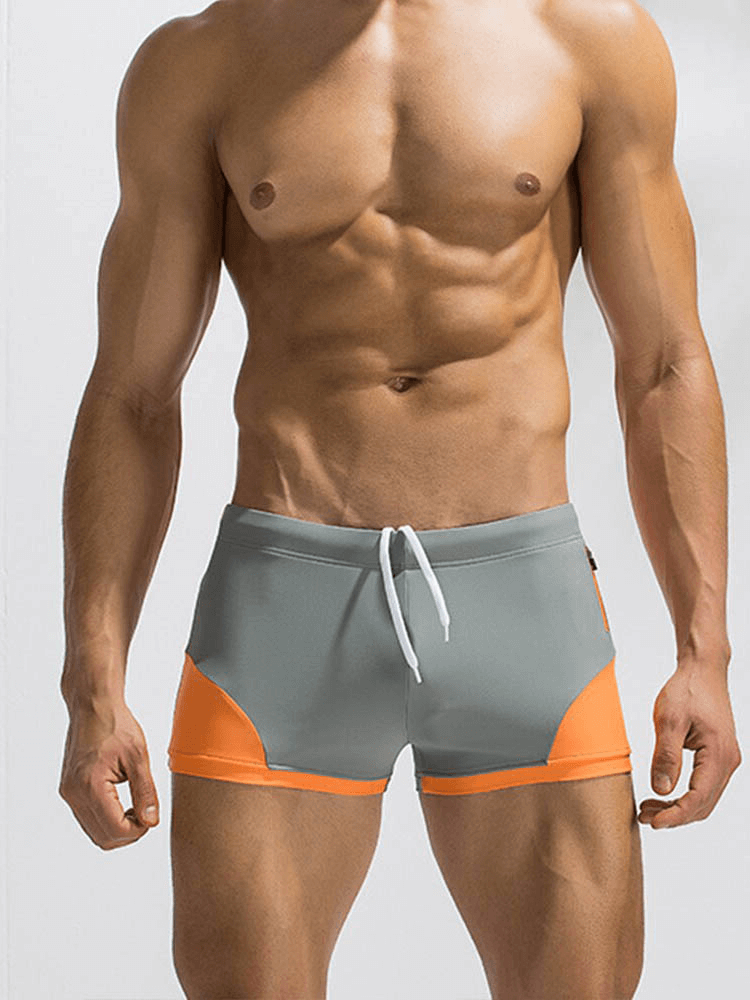 Model wears gray and orange color block swimming boxer shorts for men, showcasing high-performance materials and elastic fit.