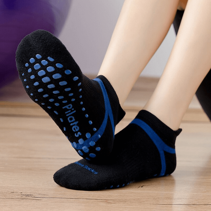 Woman wearing black anti-slip compression socks with blue accents, perfect for pilates or yoga training.
