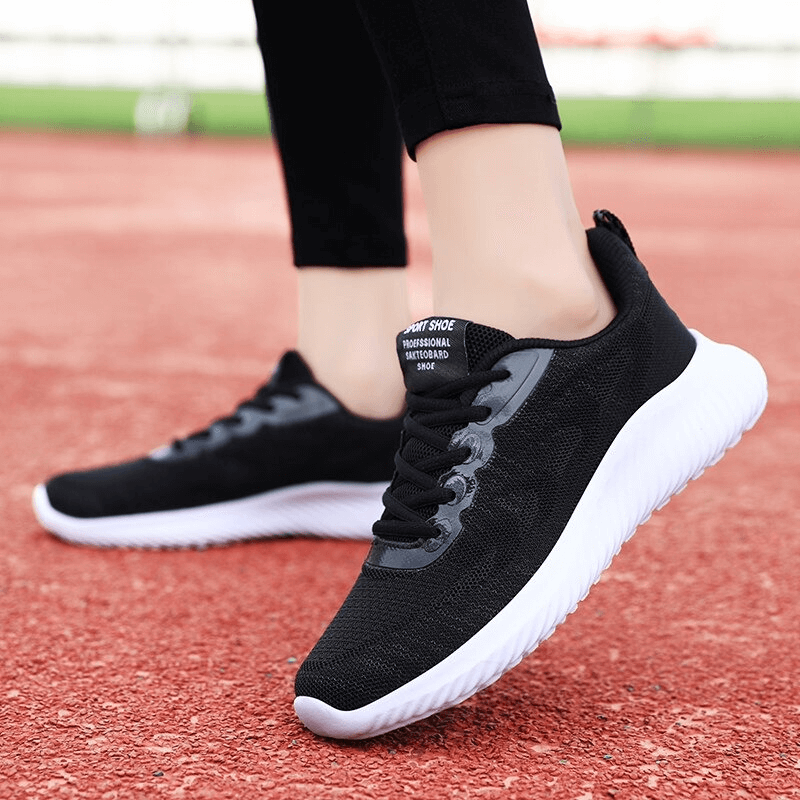 Woman wearing Doble Color Breathable Running Shoes, showing black mesh and white EVA outsole on a track. Perfect for fitness.