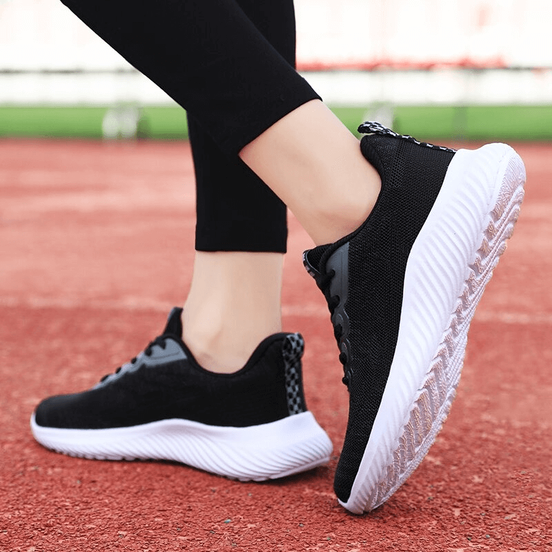 Woman wearing Doble Color breathable running shoes SF0254, black and white design, on a track, showcasing flexibility and comfort.
