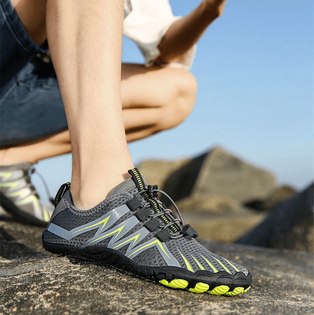 Person wearing Drainage Antiskid Sole Sports Breathable Shoes for Swimming on rocks. Stretch fabric upper, anti-skid rubber outsole.