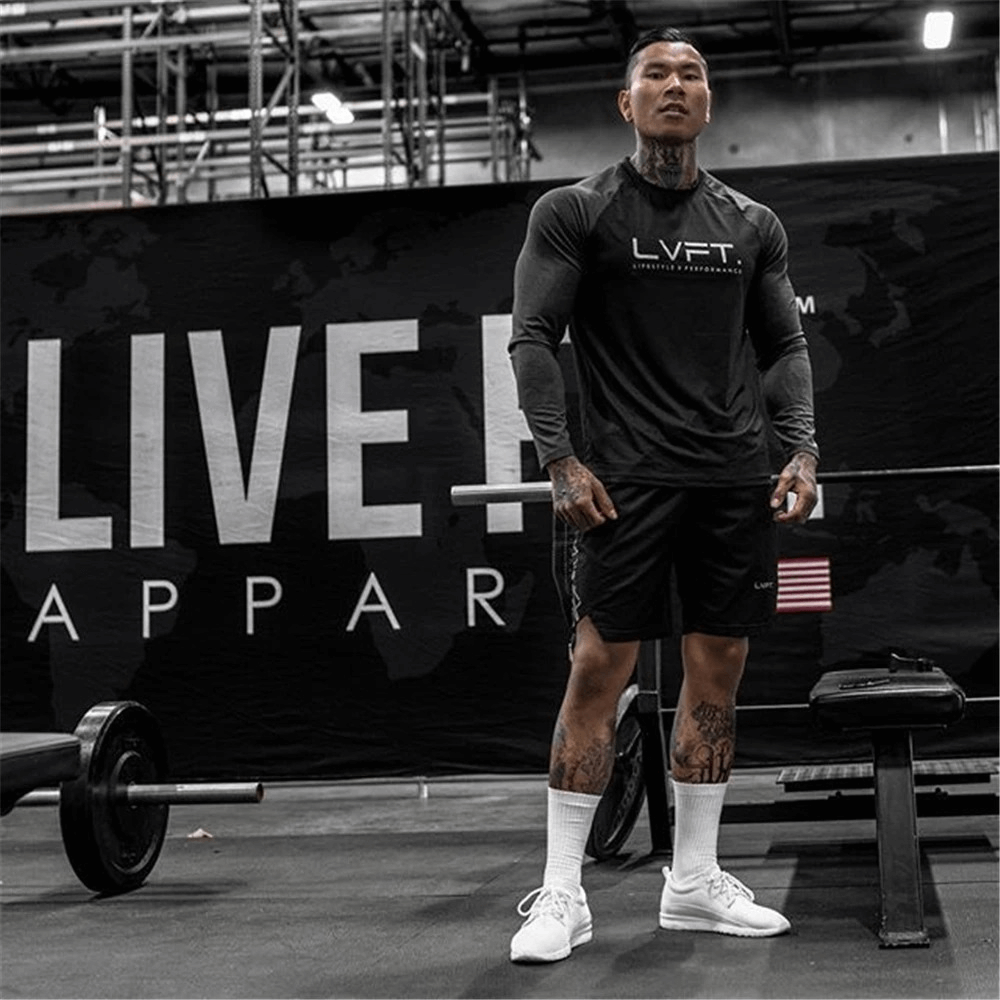 Man in gym wearing black drawstring running shorts with "LVFT" top, standing confidently by a barbell. Ideal bodybuilding outfit.