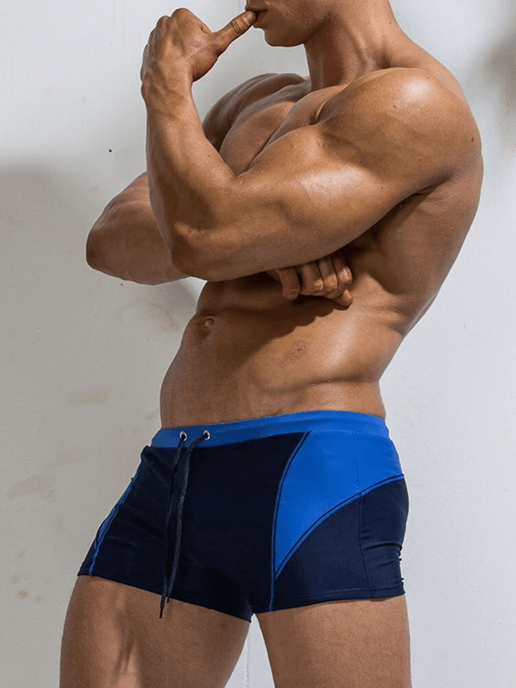 Muscular man modeling Elastic Beach Men's Swimming Trunks SF0889 in blue, showcasing durable polyester fabric and stylish design.
