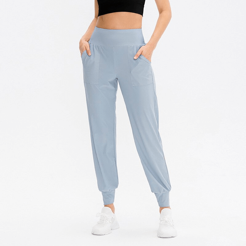 Woman wearing elastic lightweight blue sweatpants with pockets, perfect for yoga and outdoor activities, showcasing adjustable fit waistband.