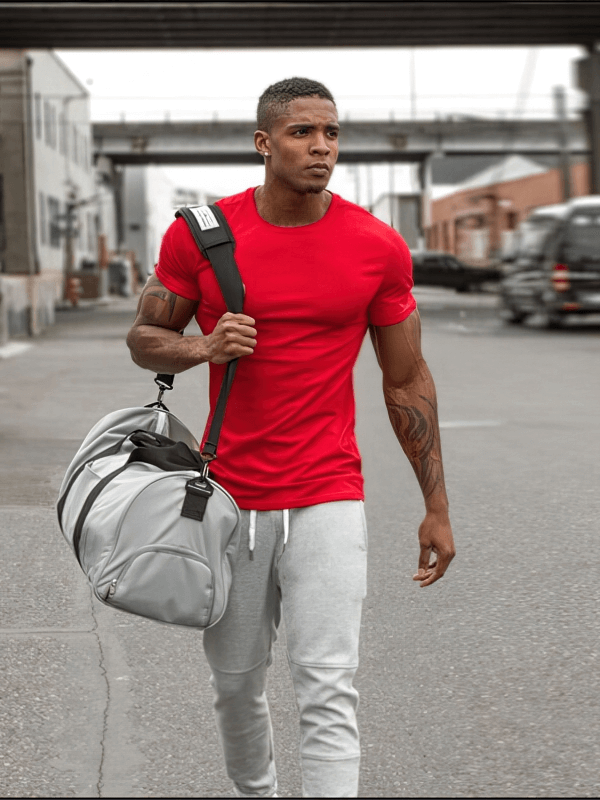 Man in red quick-dry sports t-shirt walking with gym bag, ready for workout