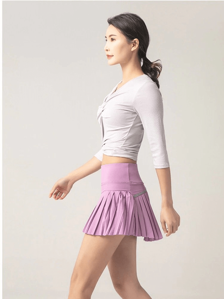 Woman wearing pink elastic pleated skirt-shorts, stylish sportswear perfect for yoga, running, and fitness activities.