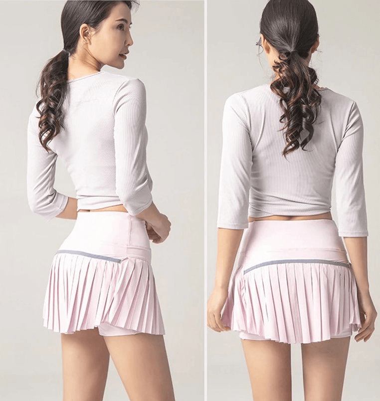 Back view of woman wearing elastic pleated skirt-shorts in light pink, featuring a sporty and stylish design perfect for active wear.