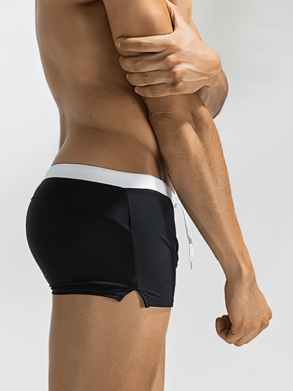 Side view of man wearing black and white elastic quick dry men's swim shorts with back pocket, ideal for water activities.