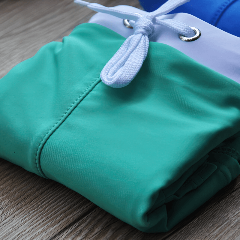 Folded green elastic quick dry men's swim shorts with a drawstring, perfect for summer adventures. Features lightweight and durable polyester.