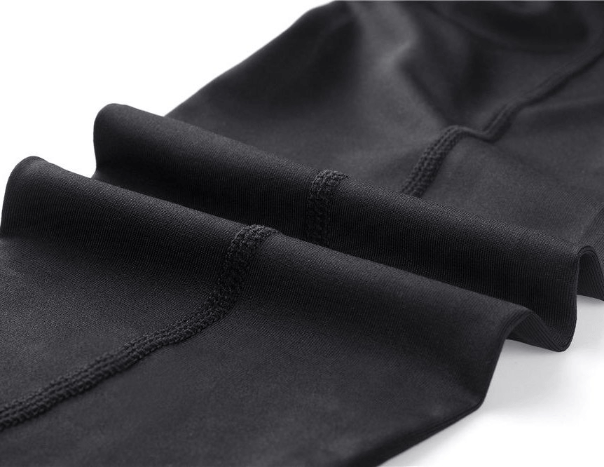 Close-up of black elastic running training pants fabric with seam detail, showing stretchy and comfortable sportswear material.