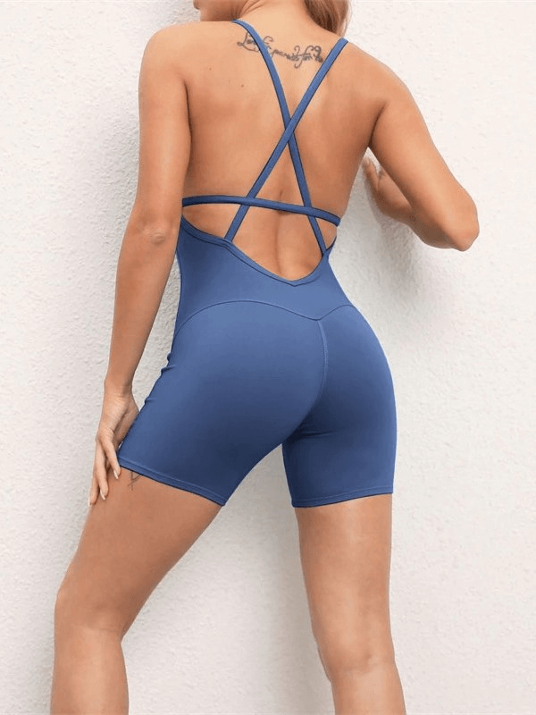 Woman wearing blue elastic sports short jumpsuit with open-back design, showcasing breathable and flexible athletic wear.