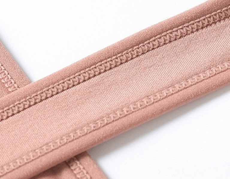 Close-up of elastic straps on women's sports top bra in beige, featuring detailed stitching design.