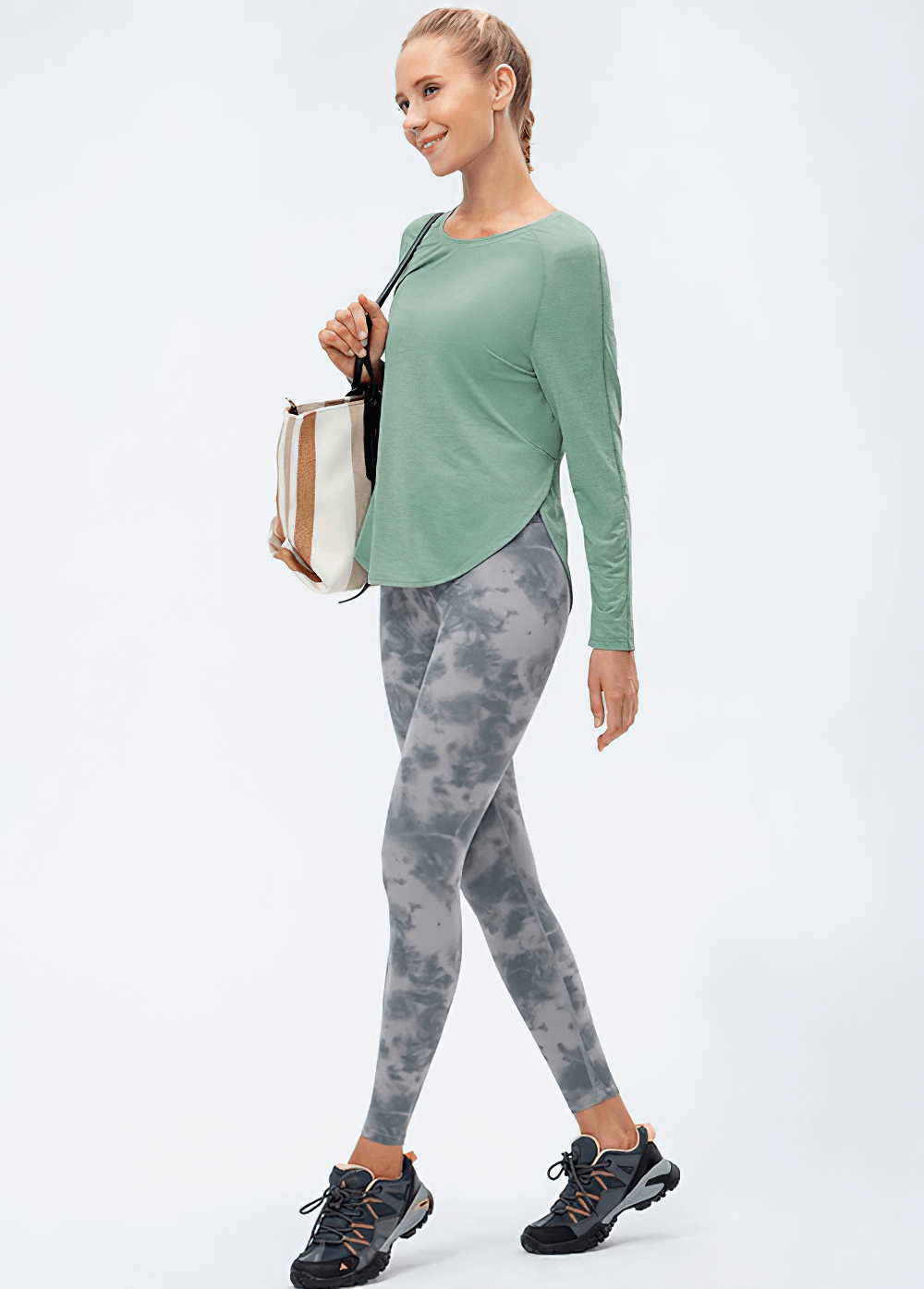 Woman in green Loose Top and patterned leggings, walking confidently with a handbag. Perfect Yoga look with comfort and style in full sleeves.
