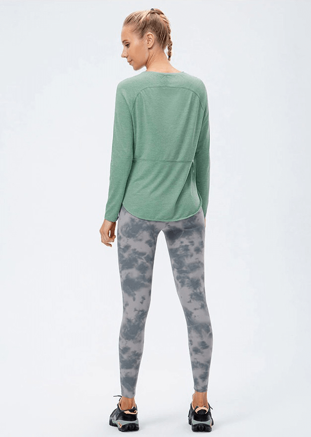 Woman wearing green Elasticity Loose Top with Draped Hem and patterned leggings, ideal for yoga workouts.