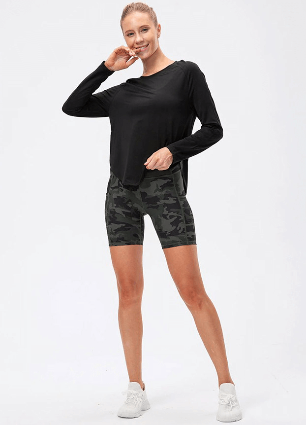 Woman wearing black loose top with draped hem and camo shorts, perfect for yoga and workouts.