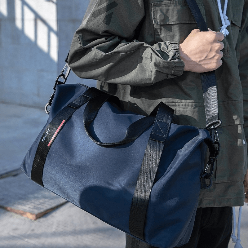 Person holding a navy blue fashion casual sports shoulder bag with black straps, perfect for lightweight travel and fitness.