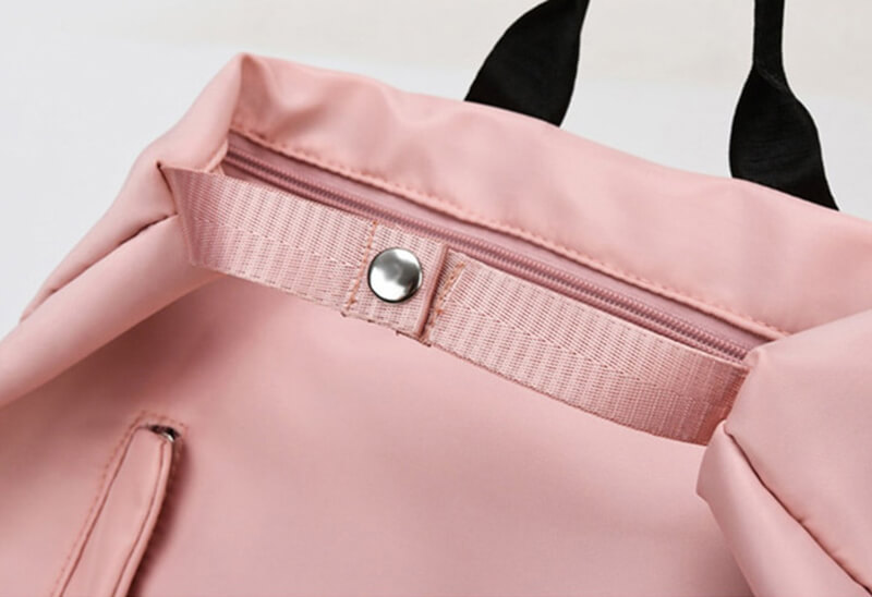 Close-up of a pink double layer drawstring waterproof backpack with a stylish snap buckle, perfect for fashion-forward adventurers.