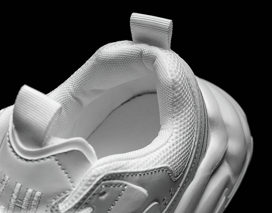Close-up of white mesh and leather sneaker with lace-up design, highlighting breathable fabric and cushioning for comfort.